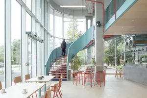 A modern industrial cafe with concrete interiors, glass walls, and metal accents.