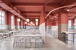 Large modern cafeteria with white tables and chairs, red painted concrete walls, and hanging spherical lights.