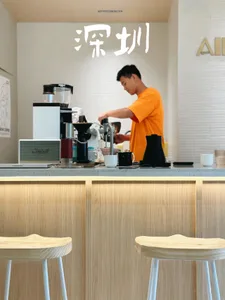 A person working at a modern coffee shop counter made of wood.
