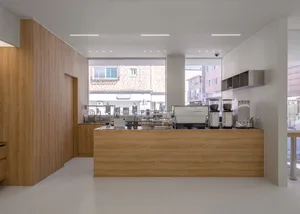 A well-lit, minimalist coffee shop interior featuring a wooden counter with coffee-making equipment.