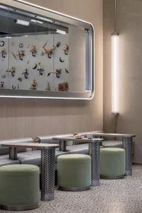 A modern interior space featuring metallic seating and a display of seashells and small sculptures.