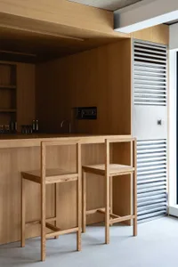 Modern minimalist kitchen with wooden cabinets and stools.