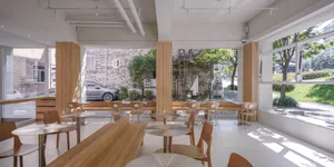 A modern restaurant interior with wooden furniture, tables, and seating.