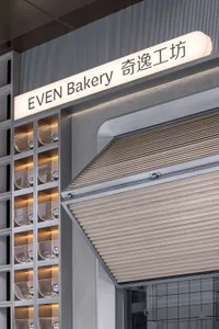 Even Bakery storefront with illuminated signage featuring metallic elements.