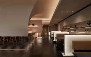 A minimalist restaurant interior with wooden tables and benches, white marble accents, and a warm, inviting atmosphere.