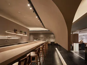 A modern restaurant bar with a concrete counter and barstools