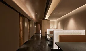 Modern restaurant interior featuring wooden seating, leather accents, and marble countertops.