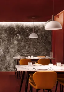 A modern industrial restaurant interior with marble walls and velvet chairs.