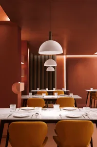 Interior design of a modern restaurant featuring marble tables, glass pendant lights, and yellow velvet chairs.