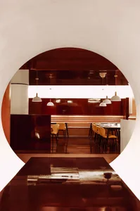 A modern restaurant interior with red metallic walls and white pendant lights.