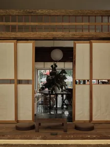 A traditional Japanese restaurant interior with paper walls, wooden beams, and a decorative plant on a round table.