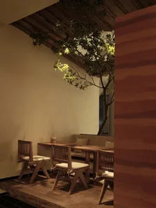 A minimalist restaurant interior featuring wooden furniture and a plant.