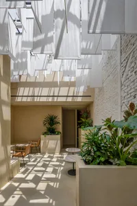 A modern-style coffee shop interior with concrete elements and hanging fabric screens.