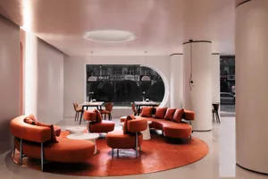 Modern coffee shop featuring orange leather seating and round tables.