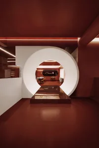 A modern restaurant interior with a large circular door leading into a dining area.