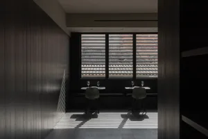 Interior of a modern restaurant with dark accents, featuring minimalist design and wooden materials.