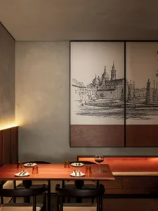 Modern restaurant interior with wooden tables, metal chairs, and glassware.