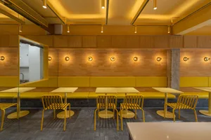 A modern restaurant with yellow decor and seating arrangements.
