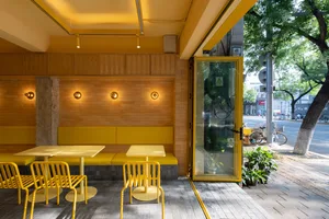 A modern restaurant interior designed with yellow seating and tables.