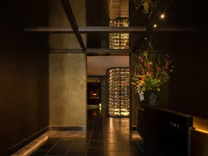 Industrial-style entrance to a restaurant, featuring glass-enclosed wine bottles and wooden walls.