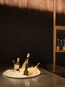 A modern bar setting with a metal counter displaying various bottles of alcohol.