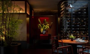 A modern restaurant interior with wooden furniture, glass shelving, and metal accents.
