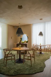 A cozy restaurant dining area with wooden tables, green carpet, and pendant lights.