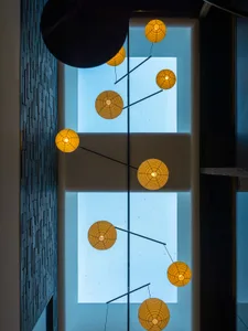 A modern interior design lamp with lights hanging from black metal rods against a blue background.