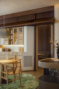 Modern kitchen with wooden cabinets and flooring, featuring glassware and decorative items on shelves.