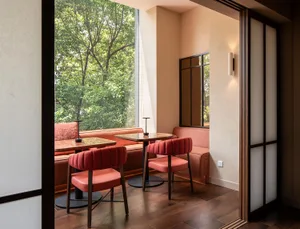 A cozy restaurant interior featuring a modern design with fabric seating and wooden accents.