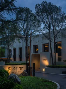 A modern building with a concrete facade and glass windows illuminated at night.