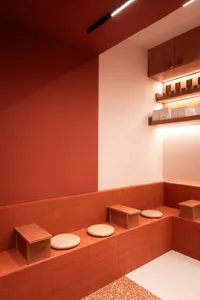 A modern coffee shop with rustic terrazzo flooring, white and terracotta walls, and wooden seating.