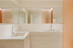 A minimalist bathroom with marble countertops and a large mirror.