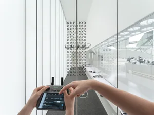 A minimalist office interior featuring glass walls and white decor.