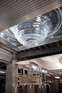 A contemporary glass installation art piece featuring a large, swirling glass vessel)
