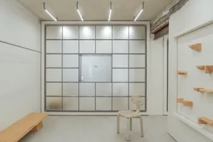 A minimalist interior with a glass window, metal frame, and wooden furniture.