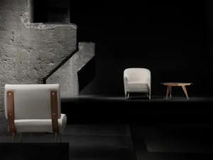 A minimalist display of white armchairs against a dark, industrial background.