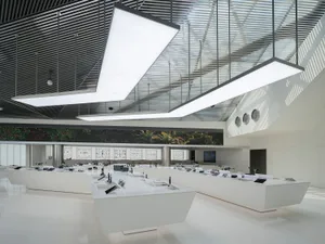 An image showcasing a modern exhibition hall featuring metallic glass walls and white display tables.
