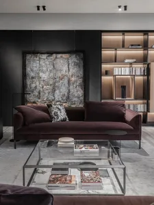Modern living room with a purple velvet couch, glass coffee table, and light wood shelves.