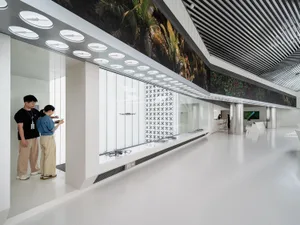People operating drones indoors in a modern office setting with glass walls and metal accents.