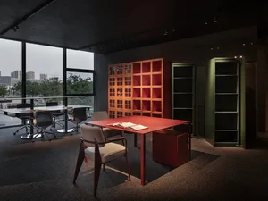 現代辦公空間，配有紅色金屬家具，並設有大型窗戶可俯瞰城市景觀。