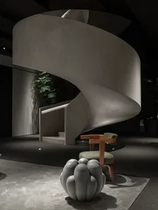 Modern, minimalist, concrete spiral staircase interior design with greenery and seating.