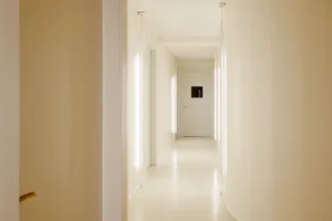 極簡風格的走廊，牆面與地板皆為中性色調，盡頭設有一扇門。