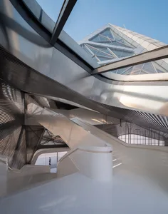 A modern indoor architectural space with glass walls, stone walls, and metal accents.