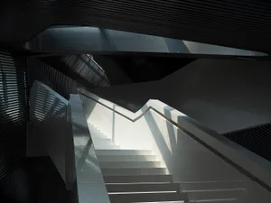 Modern, minimalist concrete staircase with metallic handrails in a contemporary architectural setting.