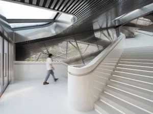 Modern concrete staircase with a white surface and a geometric ceiling design.