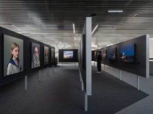 An industrial exhibition with black walls and various artworks displayed on the walls.