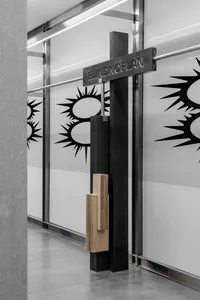 Modern minimalist interior design featuring a black-framed glass entryway with an abstract logo design.