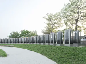 Rows of modern glass and steel structures in a park setting with greenery and trees.