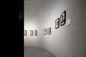 A gallery room featuring art displayed on curved white tiled walls.